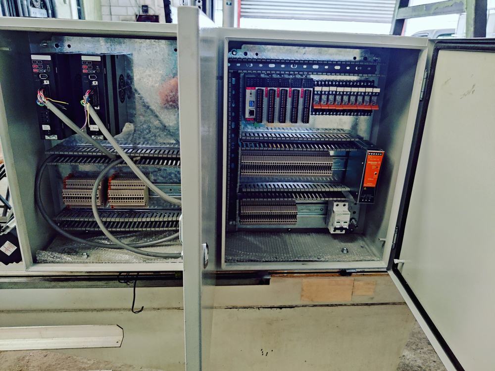 Técnico con chaleco de seguridad interviniendo un tablero de control abierto en planta