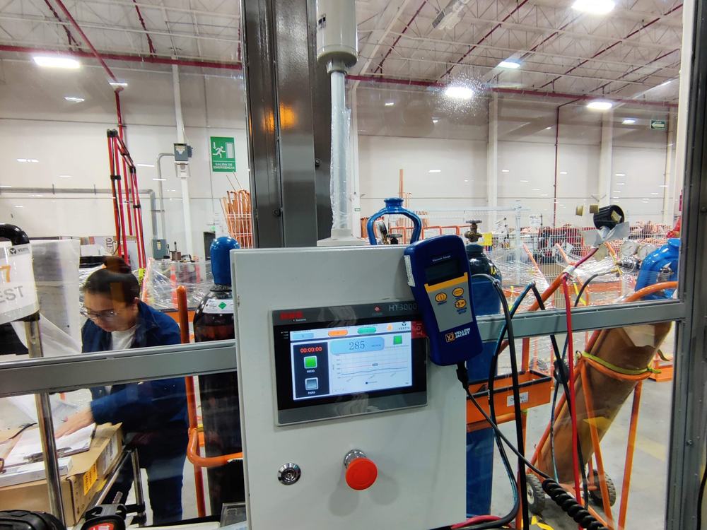 Estación de prueba de fuga y vacío con panel HMI y torre de señalización en piso de planta