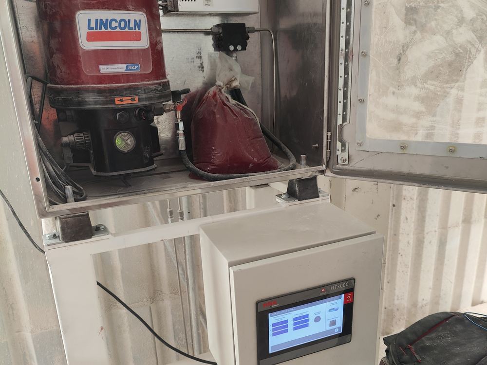 Estación de pruebas de lubricación instalada en planta: bomba Lincoln en gabinete de acero inoxidable y pantalla HMI sobre pedestal