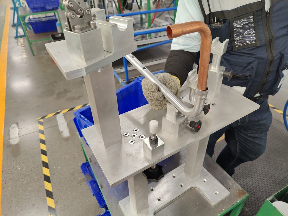 Operador colocando un tubo de cobre formado en un fixture de aluminio maquinado